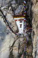 böneflaggor och ett litet kloster i bergen runt tigerboet kloster eller taktshang goemba i paro, bhutan, asien foto