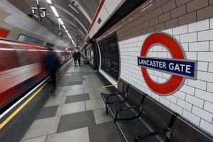 london, Storbritannien 2015, london underjordisk skylt med tåg i rörelse och folk vid lancaster gate station. foto