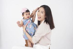 asiatisk mamma och bedårande flicka är glada på vit bakgrund foto