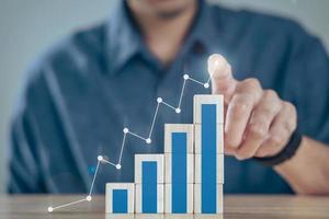 affärsman planerar att öka verksamhetens tillväxt med stack trä kub block och affärsgraf och diagram positiva indicators.target och mål affärsanalys och finansiella koncept. foto