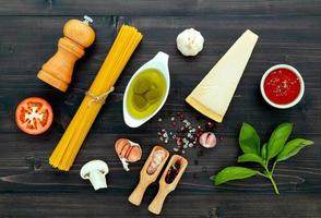 pastan på svart trä bakgrund. gul italiensk pasta med ingredienser. italiensk mat och menykoncept. foto