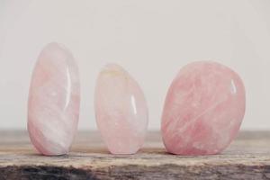 polerade kristaller rosékvarts ädelsten på ett träbord foto