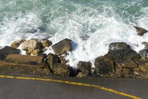 vågorna bryter på en stenig strand och bildar en spray. våg och stänk på stranden. vågor som slår mot stenar. foto
