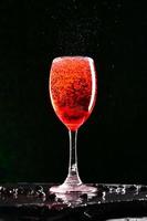 alkoholhaltiga cocktails bestående av röda fruktjuicer och sodavatten. hälls upp i ett glas vin av en professionell bartender. foto