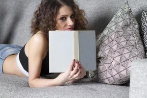 närbild av liggande kvinna läser bok avkopplande hemma foto