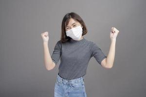 porträtt av ung vacker asiatisk kvinna som bär en kirurgisk mask över studiobakgrund covid19 pandemi och luftföroreningar foto