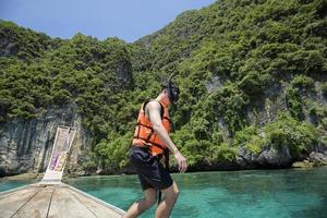 en aktiv man på thailändsk traditionell longtailbåt är redo att snorkla och dyka, phi phi-öarna, thailand foto