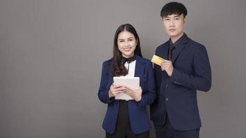 porträtt av unga asiatiska affärsmän som håller kreditkort på grå studiobakgrund foto