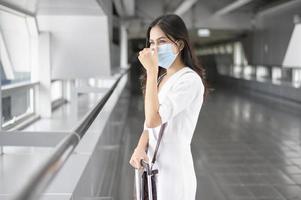 en resenskvinna bär skyddsmask på den internationella flygplatsen, resor under covid-19-pandemin, säkerhetsresor, socialt avståndsprotokoll, nytt normalt resekoncept