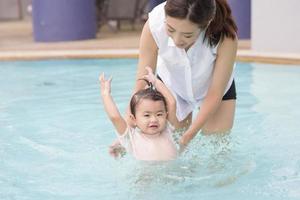 en glad asiatisk mor och dotter njuter av att simma i poolen, livsstil, föräldraskap, familjekoncept foto