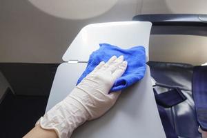 Närbild hand bär handskar rengöring flygplan för covid-19 förebyggande pandemi