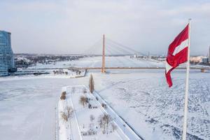 panorama över riga stad med en stor lettisk flagga i förgrunden under solig vinterdag. foto