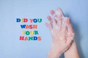 färgad text tvättade du händerna bredvid händerna i skum på en färgad bakgrund foto