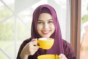 muslimsk kvinna med hijab arbetar med bärbar dator i kaféet foto