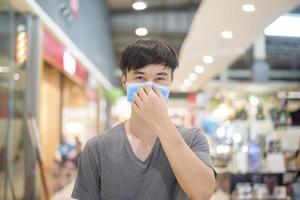 asiatisk man bär kirurgisk mask i köpcentrum