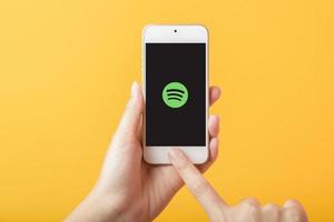 kvinna hand som håller smart telefon med spotify logotyp på apple iphone se foto