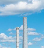 rör av ett industriföretag mot en blå himmel med moln. skorsten utan rök foto