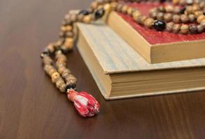 muslimska bönepärlor och Koranen isolerad på en träbakgrund. islamiska och muslimska begrepp foto