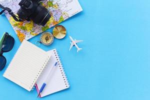 resebakgrundskoncept - planering av viktiga semesterreseartiklar sommarresetillbehör med kamera solglasögon kompasskarta anteckningsbok kaffemugg och flygplan för resenärs på bakgrund foto
