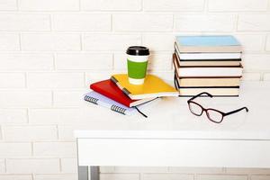 arbetsyta och utbildningstillbehör på bordet. kopp kaffe, böcker, glasögon, anteckningsböcker, hörlurar. stam utbildning foto