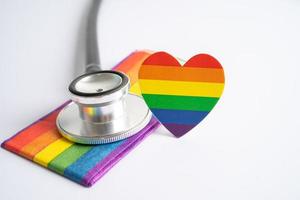 svart stetoskop med regnbågsflagga hjärta på vit bakgrund, symbol för hbt pride månad fira årliga i juni social, symbol för homosexuella, lesbiska, bisexuella, transpersoner, mänskliga rättigheter och fred. foto