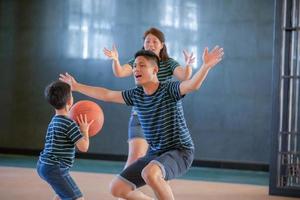 asiatisk familj som spelar basket tillsammans. lycklig familj som spenderar ledig tid tillsammans på semester foto