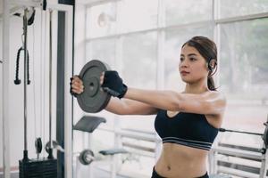vacker muskulös fit kvinna som tränar byggande muskler och fitness kvinna gör övningar i gymmet. fitness - begreppet hälsosam livsstil foto