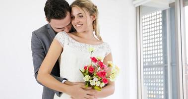 älskare ger blommor till bruden och kysste glada och par älskar stående i bröllop studio foto