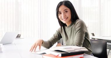 asiatiska kvinnor studenter ler och läser bok och använder anteckningsbok för hjälper till att dela idéer i arbetet och projektet. och granska också boken före tentamen foto