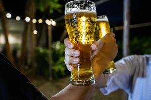 asiatisk grupp vänner festar med alkoholhaltiga öldrinkar och ungdomar som njuter i en bar och rostar cocktails och klirrande glas foto