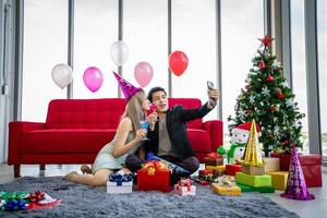 Asiatisk parälskare ger en presentask och tar en selfie med mobilsmartphone med julklapp på jullov och gott nytt år patty foto