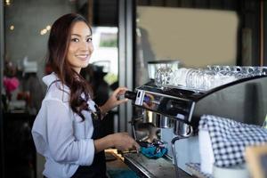 asiatiska kvinnor barista leende och använda kaffemaskin i kafédisk - arbetande kvinna småföretagare mat och dryck café koncept foto
