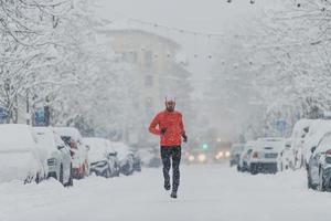 ung man löpare under ett snöfall i staden foto