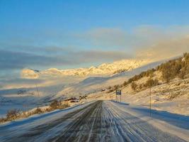 körning vid gyllene soluppgång genom berg och by i norge. foto