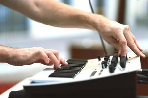 en synthesizerspelare under en konsert flyttar rattar och styr ljudet foto