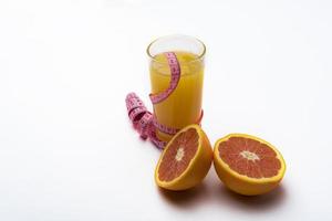 ett glas apelsinjuice på en vit bakgrund med centimeter och grapefrukt. foto