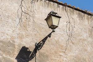 gammal stadslykta på väggen. vintage järnlykta, utomhus trädgård gata vägg metall elektrisk lampa i stan eller byn. foto