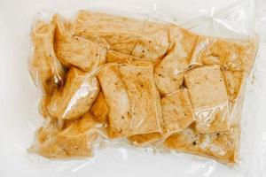 tofu med kryddor i en plastförpackning på en vit bakgrund. toppvy. kopiera, tomt utrymme för text foto