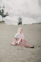vacker islamisk kvinnlig modell som bär hijabmode, en modern bröllopsklänning för muslimsk kvinna går längs sanden och havet. en asiatisk tjejmodell som använder hijab som har roligt på stranden. foto förbröllop