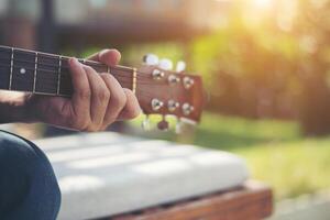 närbild av man hand spelar akustisk gitarr. foto