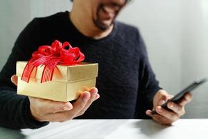 gåva ger kreativa hand välja och hand med gåva. presentleverans, överraskning, med smart telefon på mable skrivbord, filterfilmeffekt foto