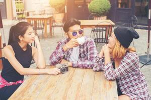 grupp unga hipster som sitter på ett kafé, unga glada vänner har roligt medan de tar tid tillsammans, njut av semesterfrihet. foto