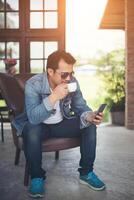 ung man med smartphone ler avkopplande på café. foto