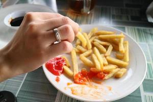 kvinnas hand som håller pommes frites full av sås foto