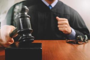 rättvisa och lagkoncept. manlig domare i en rättssal slår klubban, arbetar med digital surfplatta med dockningstangentbord på träbord, filtereffekt foto