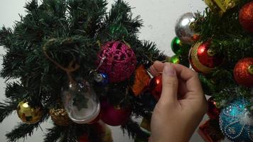 hälsning säsong concept.hand inställning av ornament på en julgran med dekorativt ljus foto
