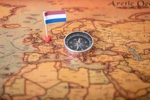 Nederländernas flagga och kompass på världskartan. foto