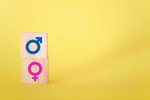manliga och kvinnliga ikonsymboler på träblock mot gul bakgrund. foto