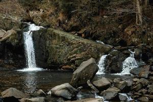 litet forsande vattenfall bland klipporna och skogen. vackert bergslandskap. kopiera, tomt utrymme för text foto