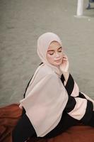 vacker islamisk kvinnlig modell som bär hijabmode, en modern bröllopsklänning för muslimsk kvinna som sitter i sanden och stranden. porträtt av en asiatisk tjejmodell med hijab som har kul på stranden med träd foto